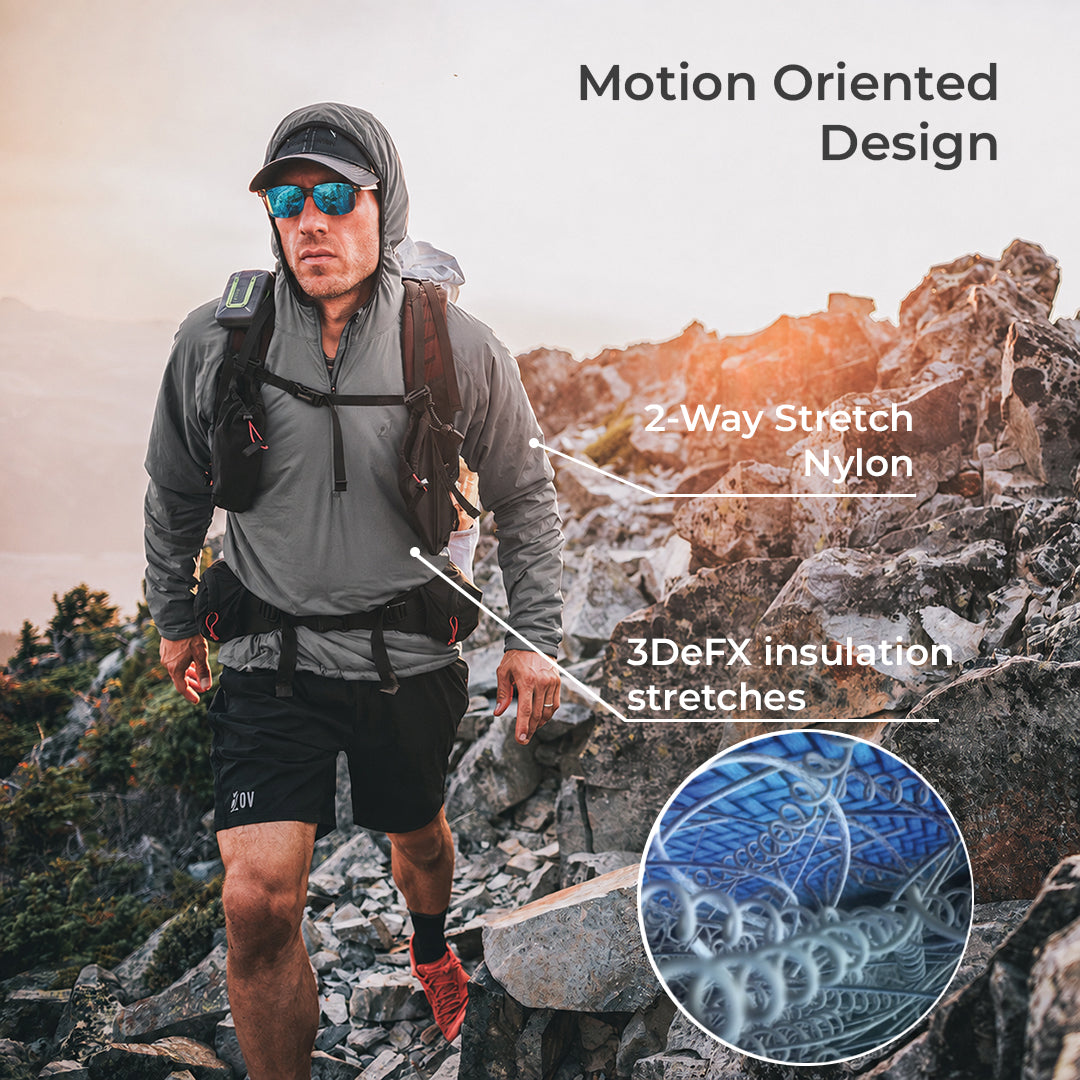 A man wearing a gray hooded technical jacket and black shorts hikes on a rocky mountain trail, with text overlays reading 'Motion Oriented Design' and '2 Way Stretch Nylon' plus a circular inset showing the fabric stretch detail.