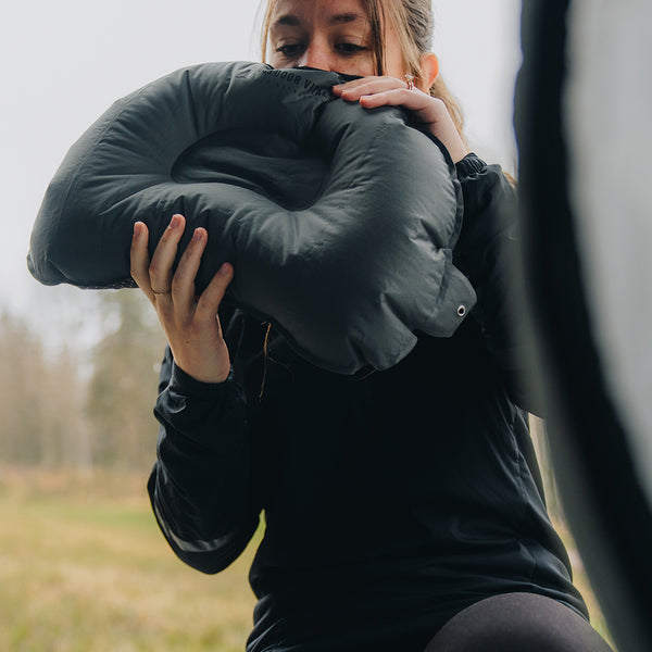 Woman inflating the Outdoor Vitals ultralight backpacking pillow inside a tent.