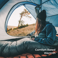 hiker sits inside blue 15 degree quilt in tent looking out the door. Callout text says, "Comfort Rated Warmth."