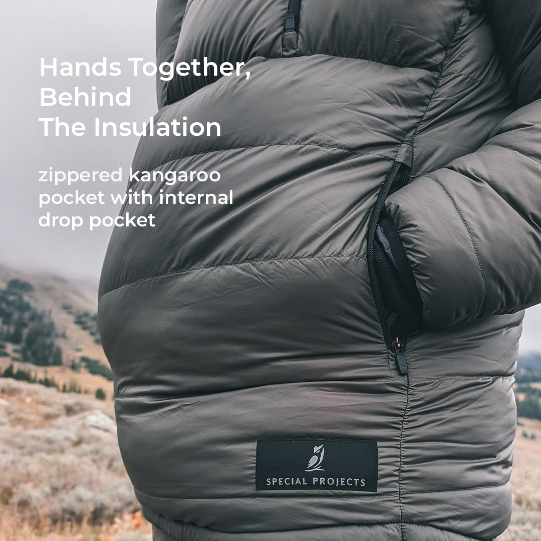 man stands with hands in kangaroo pocket of puffy down anorak jacket