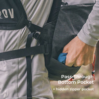 close view of hiker retrieving gear form pass-through bottom pocket beneath his fastpack. Text also describes a hidden zipper pocket within the pass-through pocket.